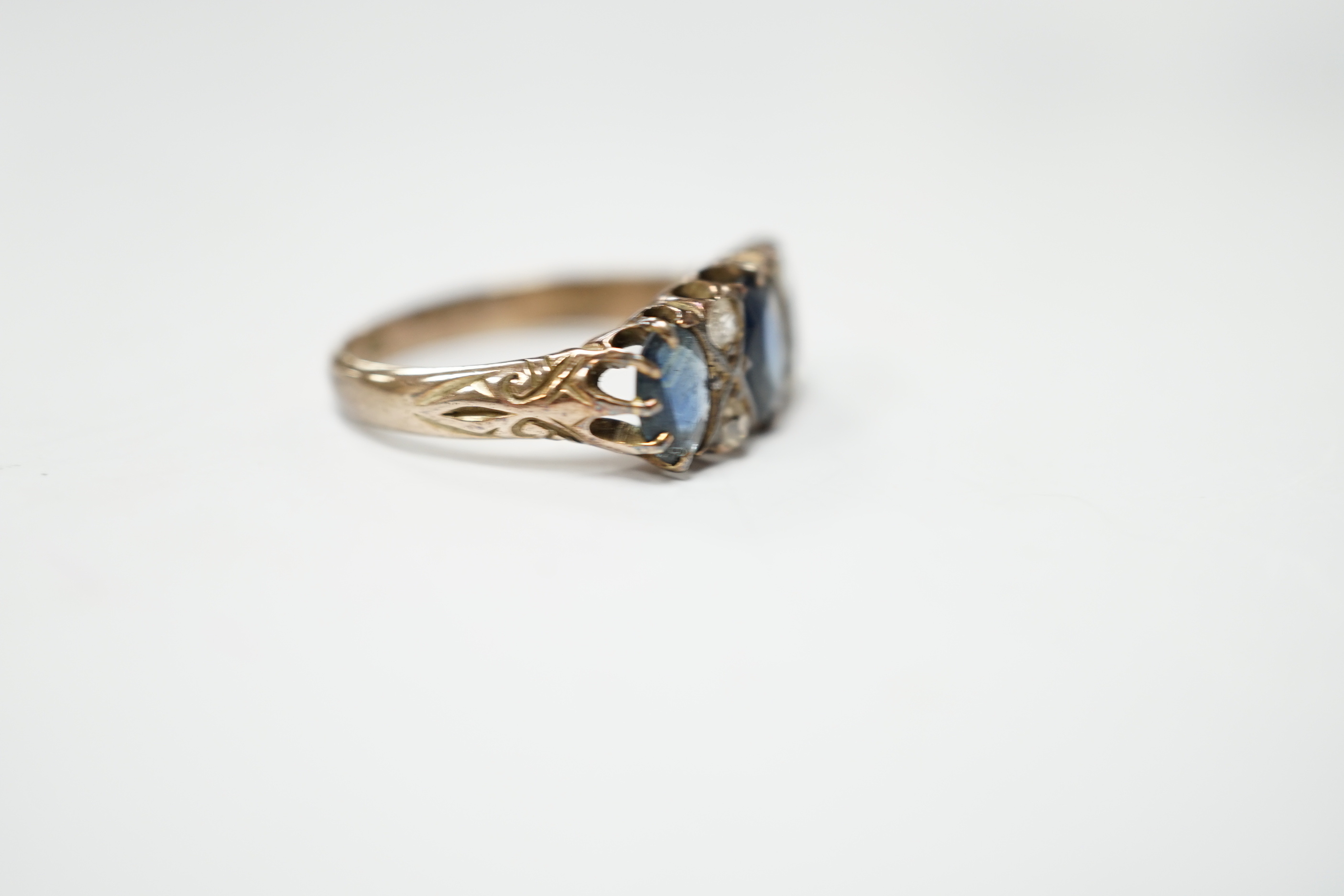 An early 20th century 18ct and graduated three stone sapphire set half hoop ring, with diamond chip spacers, size P, gross weight 3.8 grams.
